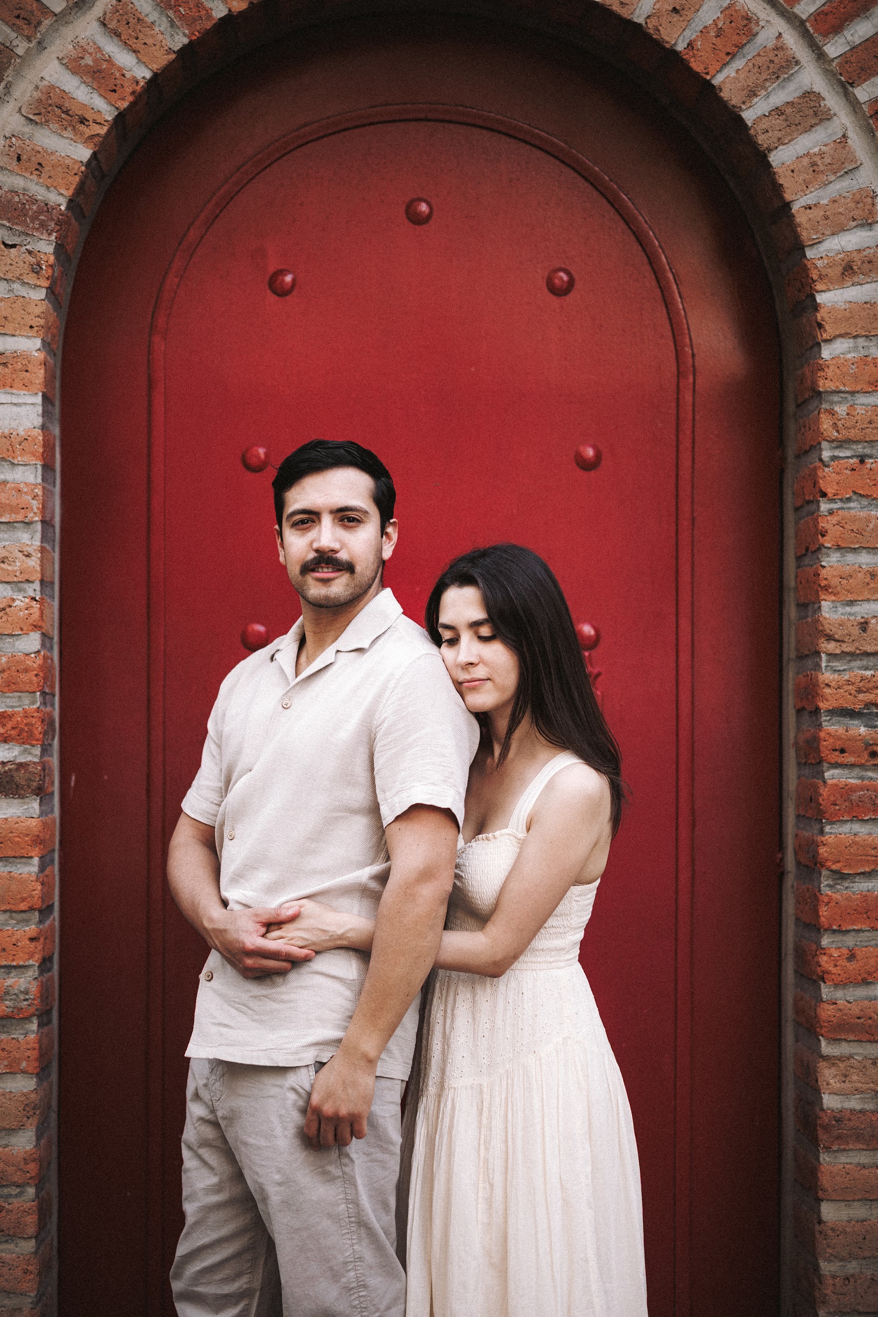 Retrato de la pareja frente a una puerta roja.