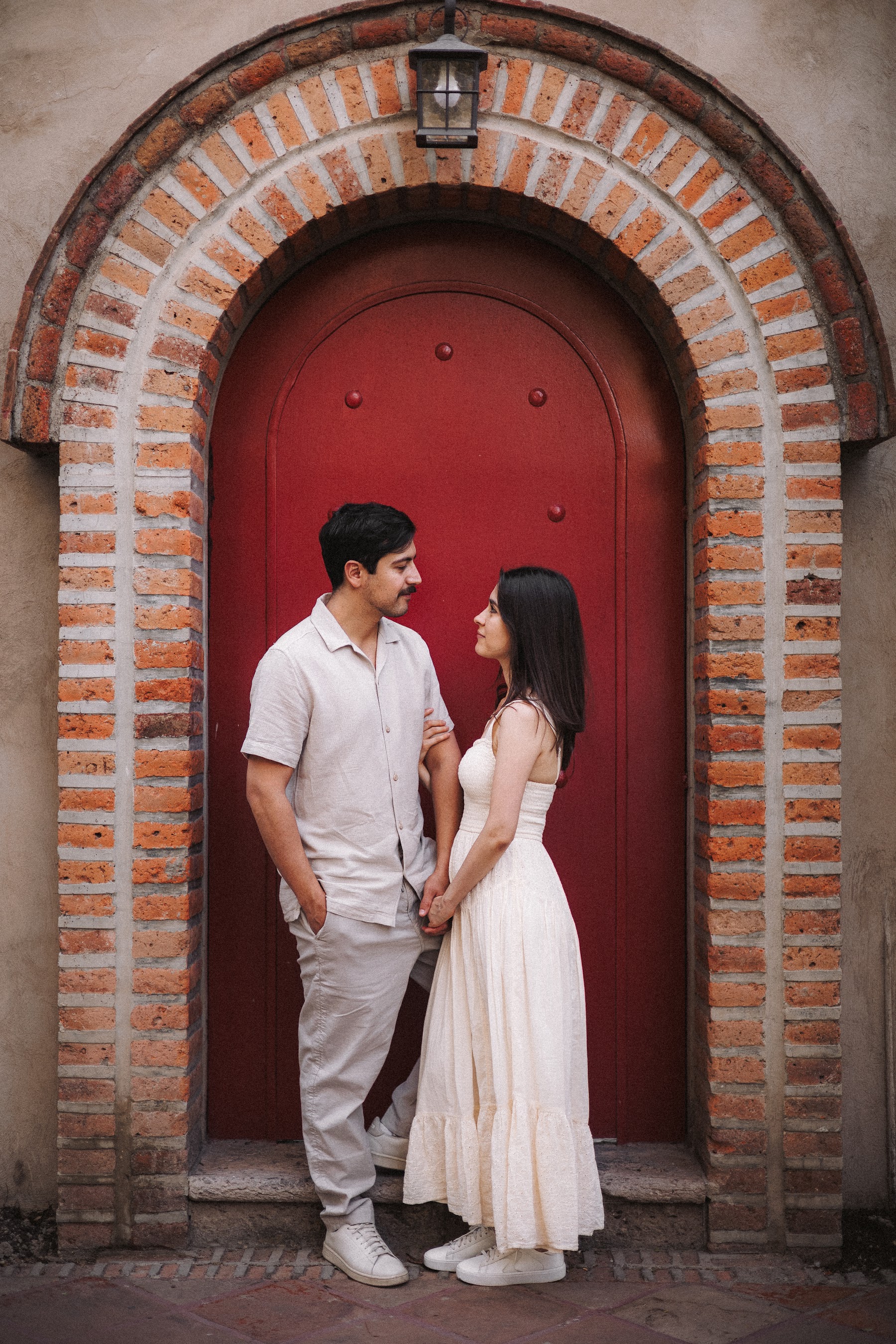 Los novios se miran frente a una fachada de ladrillo.