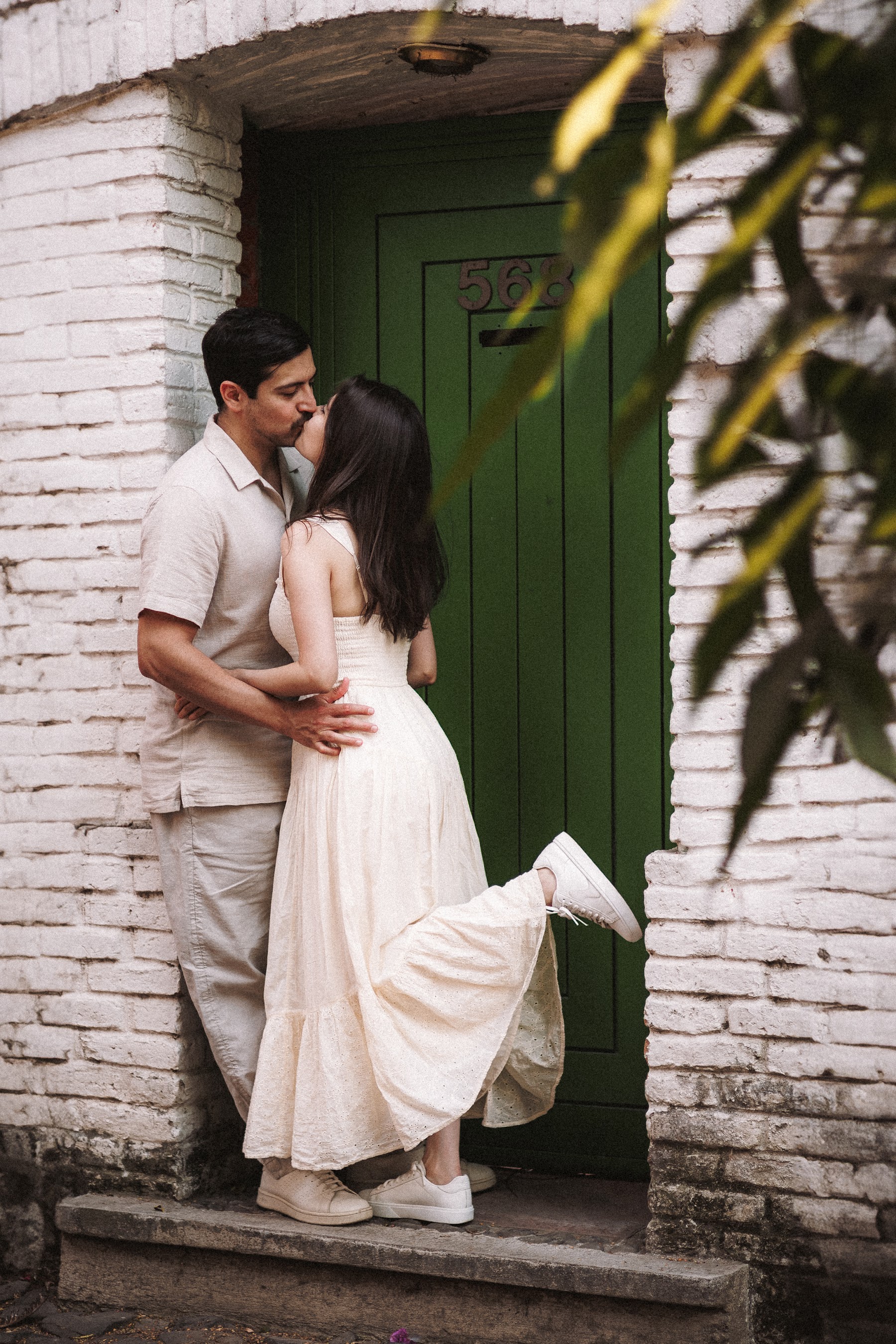 Arcelia y Adolfo comparten un beso frente a una puerta verde.