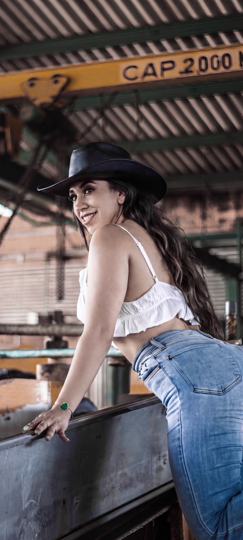 Retrato editorial de mujer con sombrero junto a un vehículo