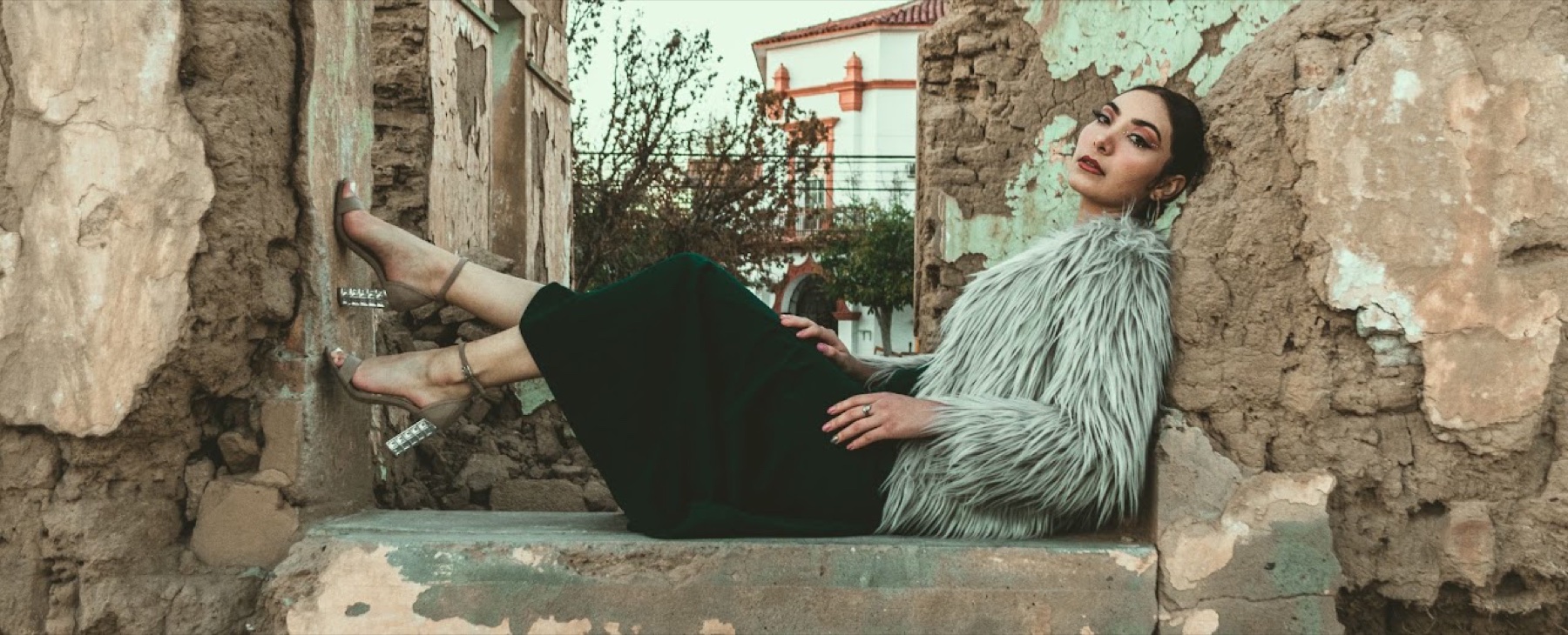 Mujer con atuendo verde posando entre muros de piedra