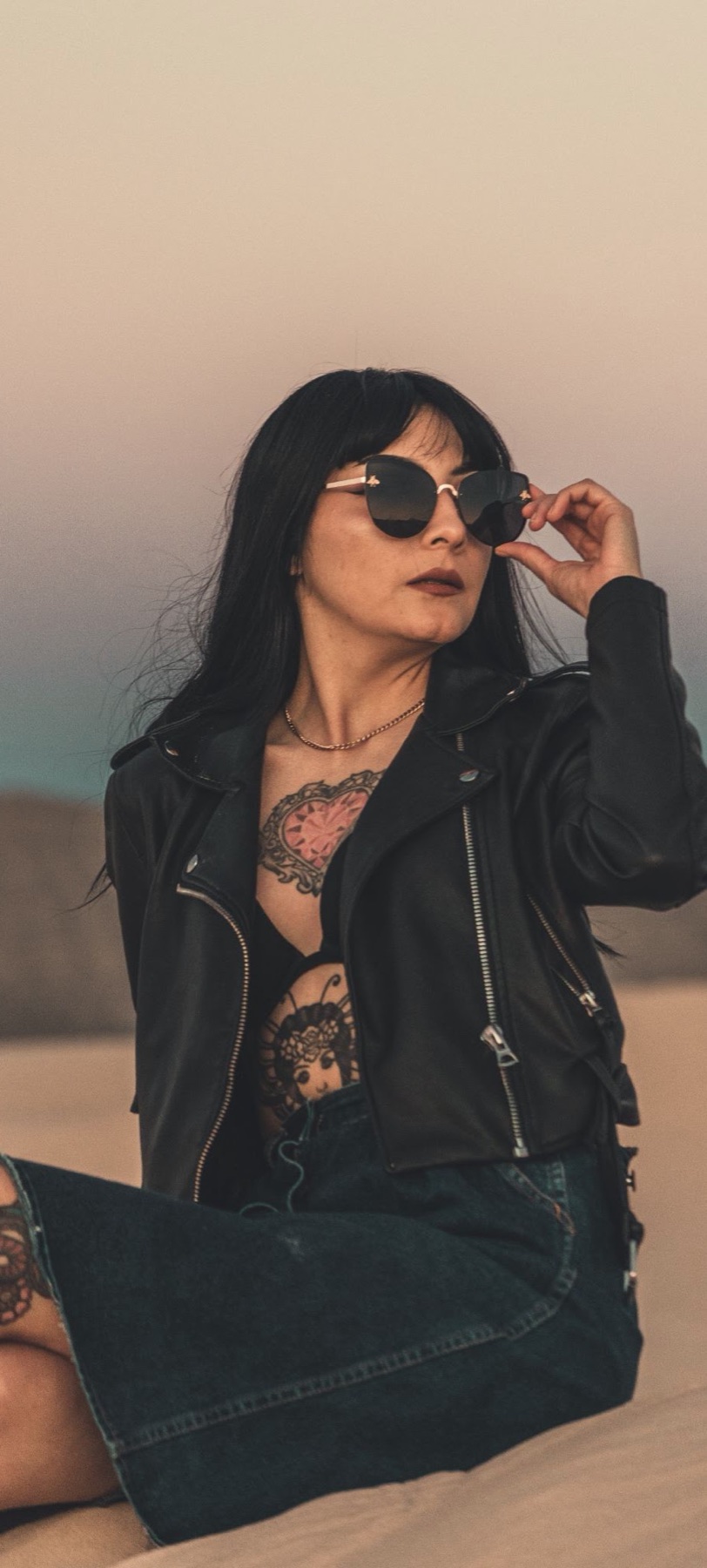 Mujer con lentes oscuros posando con un atuendo negro