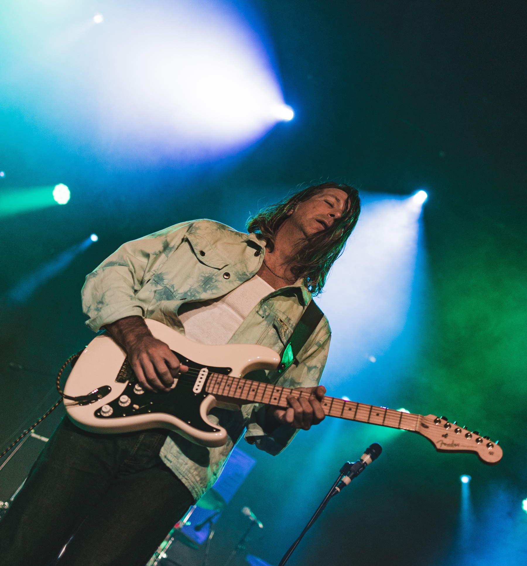 Guitarrista sobre el escenario bajo luces verdes