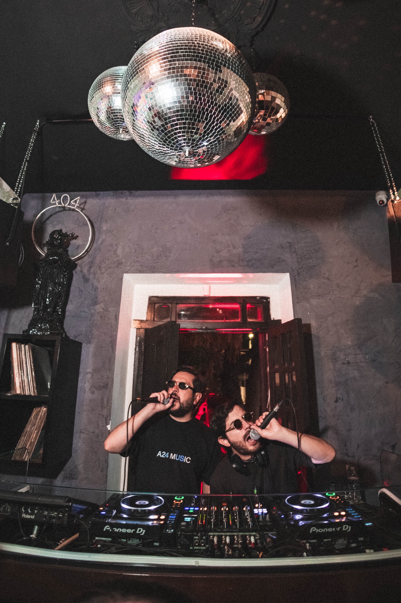 Dos DJs cantando bajo bolas de espejo