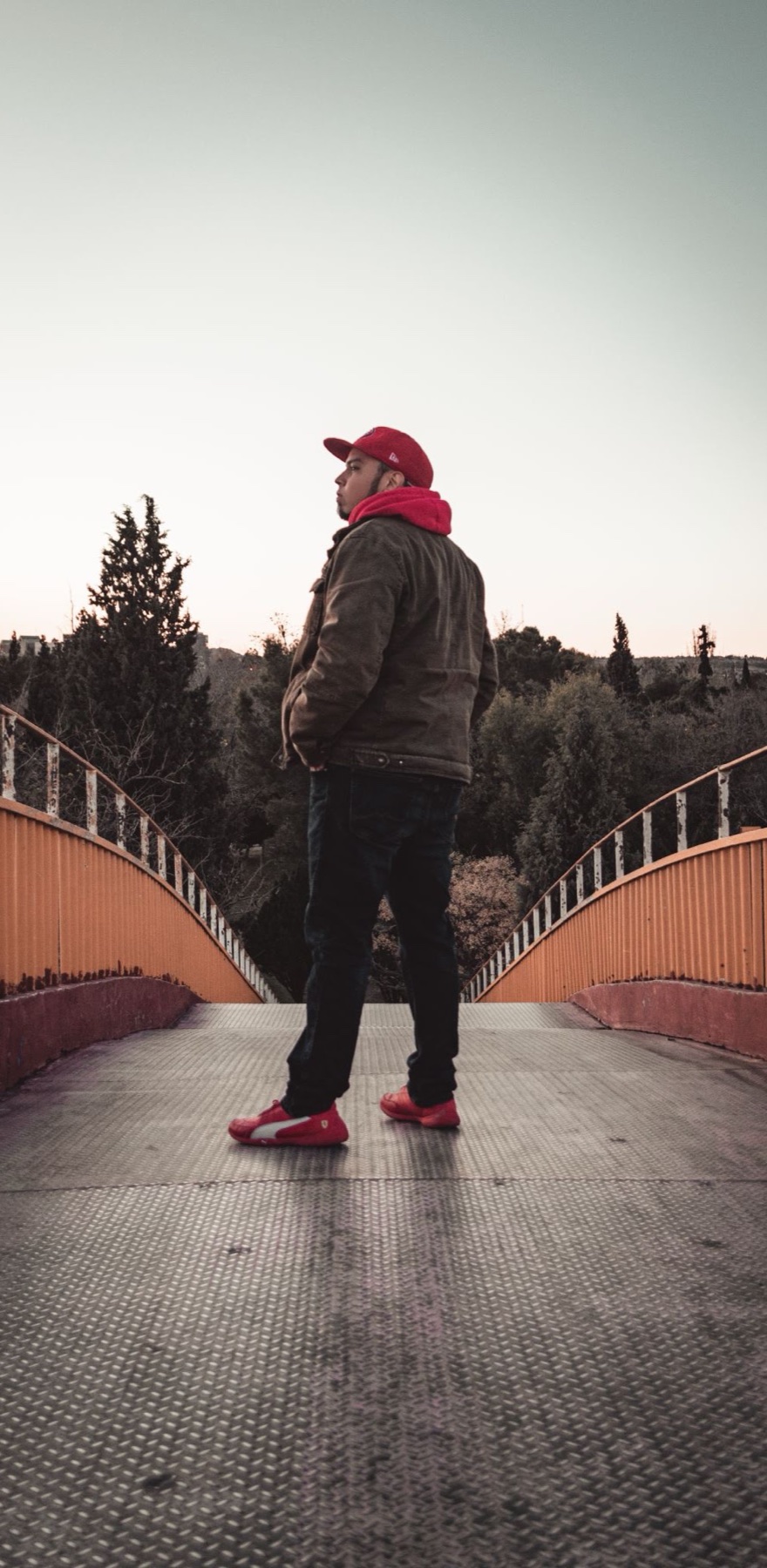 Figura con gorro rojo caminando sola sobre un puente