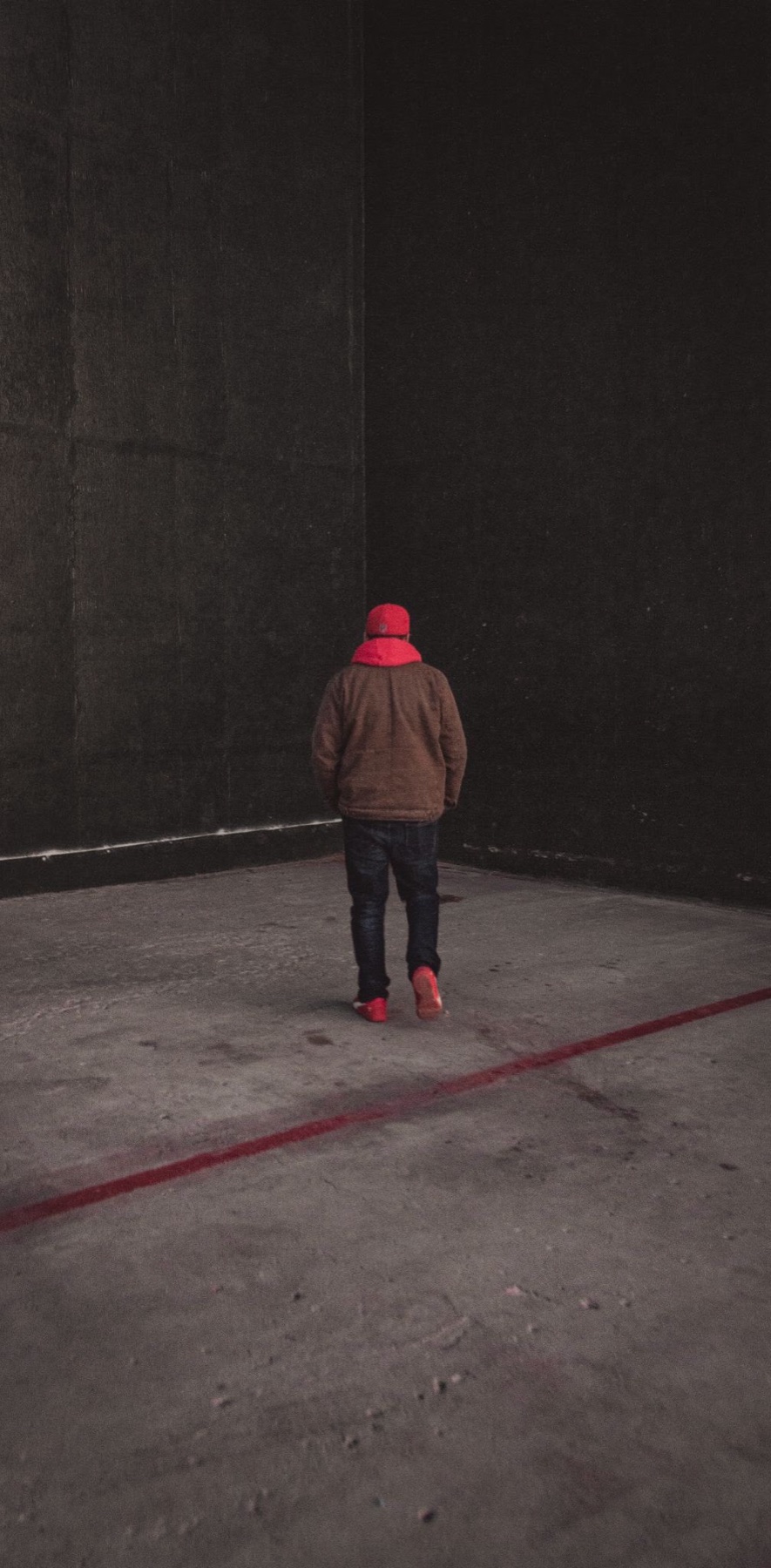 Figura con gorro rojo aislada en un espacio urbano oscuro