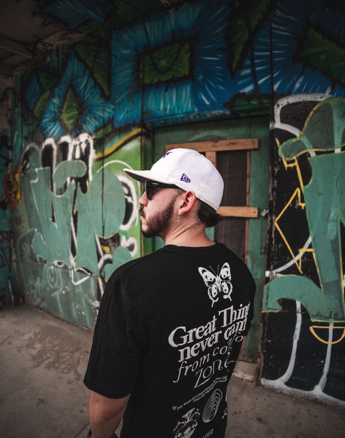 Hombre de espaldas frente a una pared cubierta de grafiti