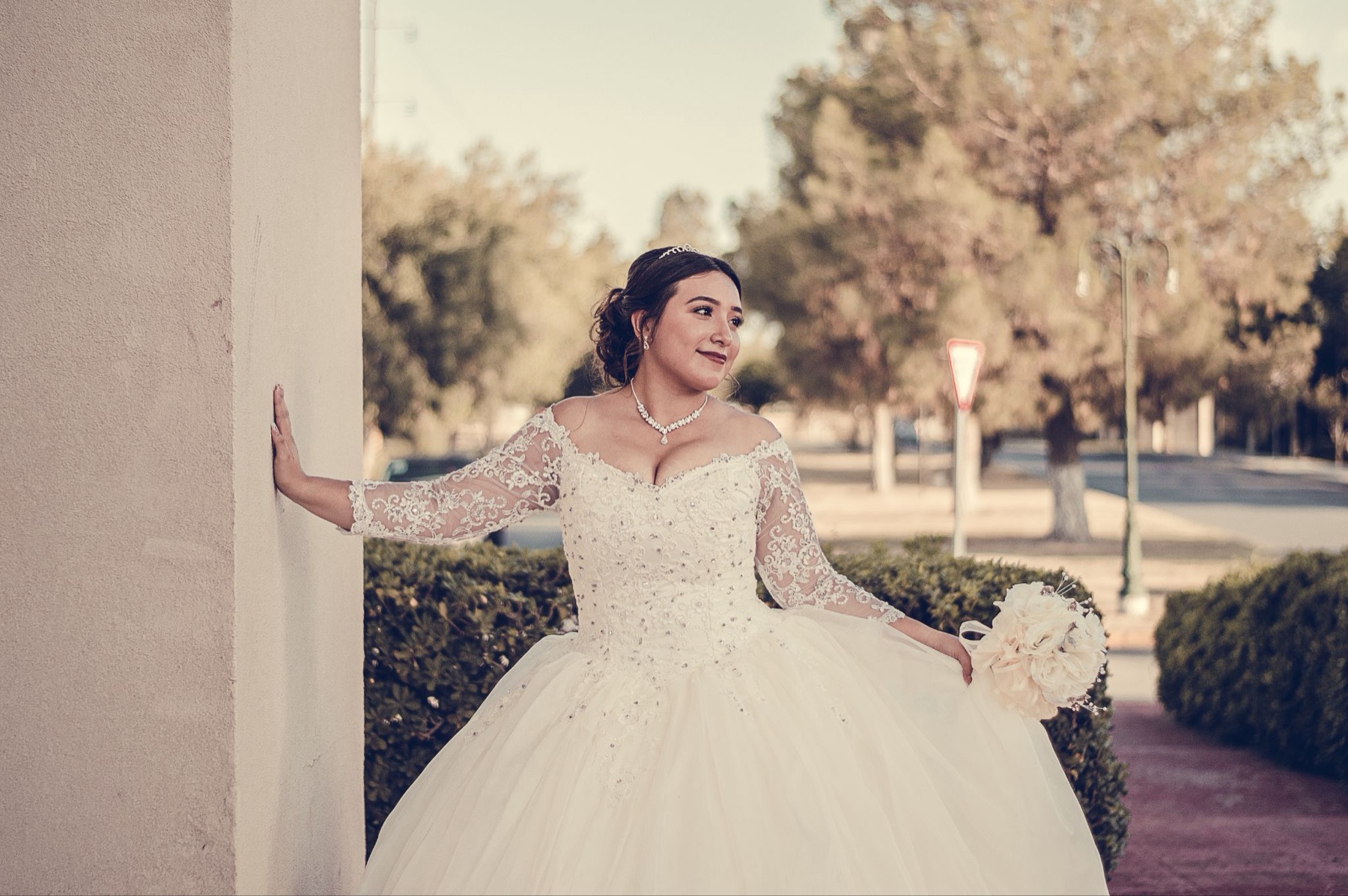 Quinceañera con vestido blanco bajo un gran arco de piedra