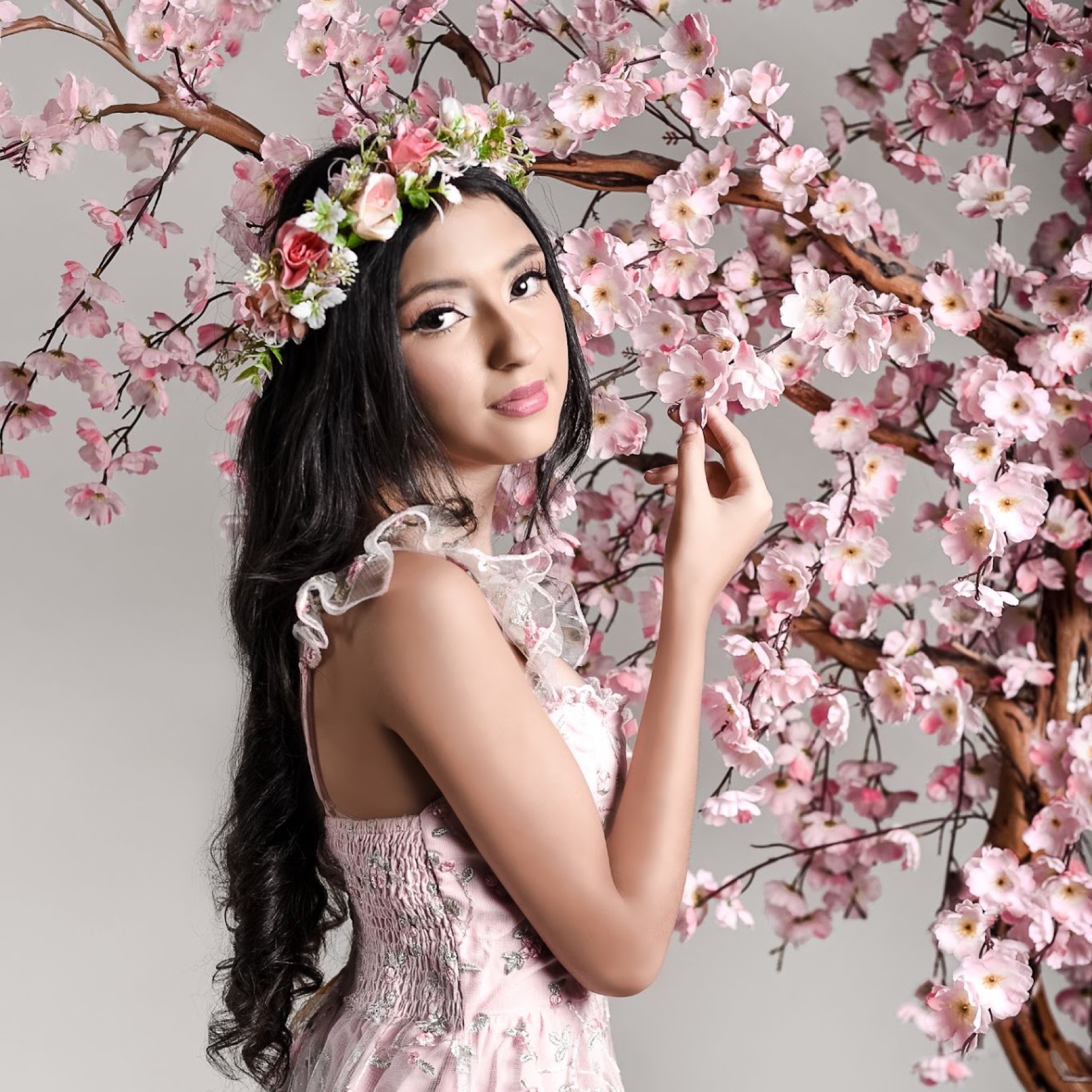 Retrato de quinceañera entre flores rosas de estudio
