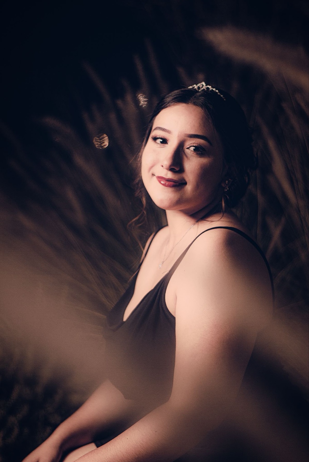 Retrato artístico de quinceañera entre sombras y tela translúcida