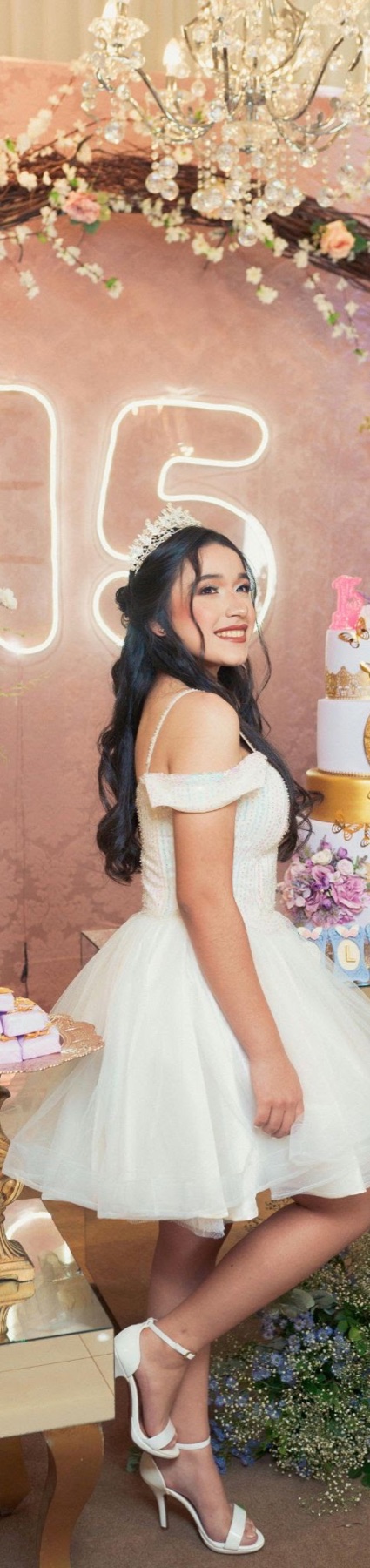 Quinceañera de cuerpo completo junto al letrero de quince años